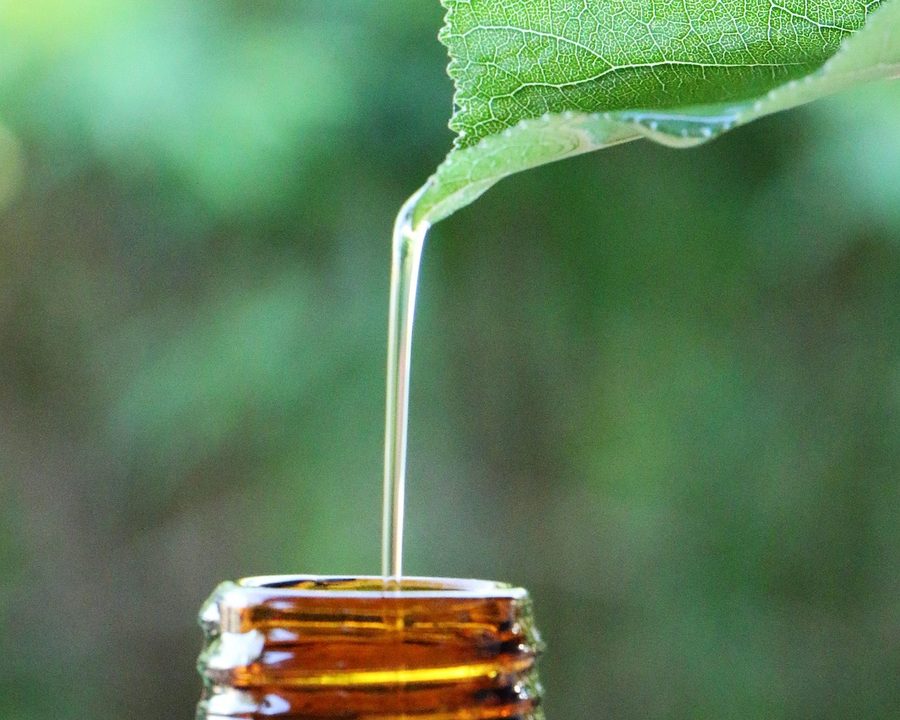 Huile naturelle versée depuis une feuille dans un flacon en verre ambré, sourcing d'arômes et huiles naturelles en Thaïlande